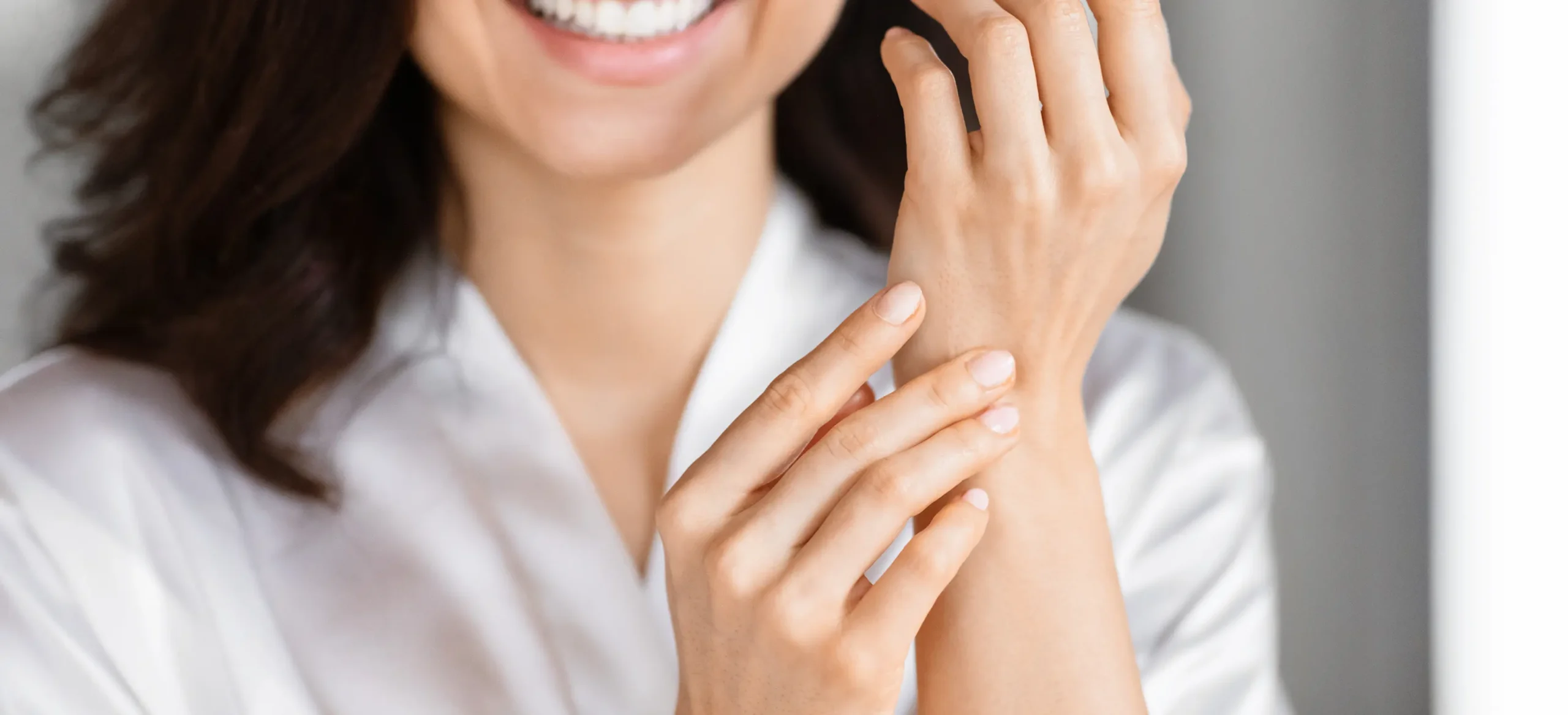 A woman in a white bathrobe applying Sarna Calm + Cool Anti-Itch Lotion on her wrists